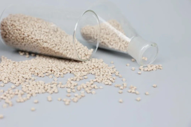 Light coloured PEEK resin pellets spilling from glass containers