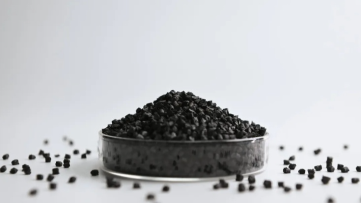 Black material pellets piled in a glass dish